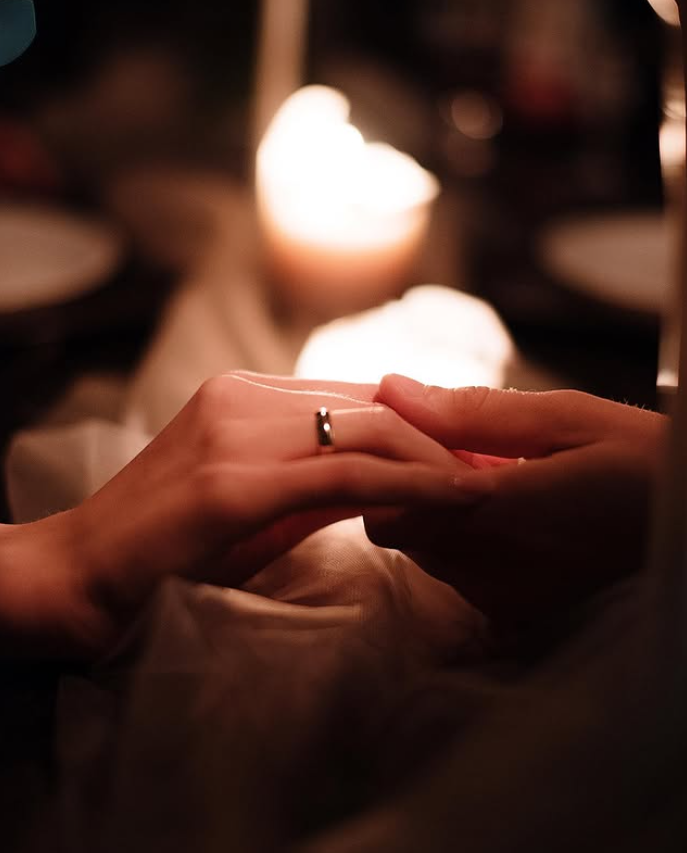 Hands holding a ring near candlelight